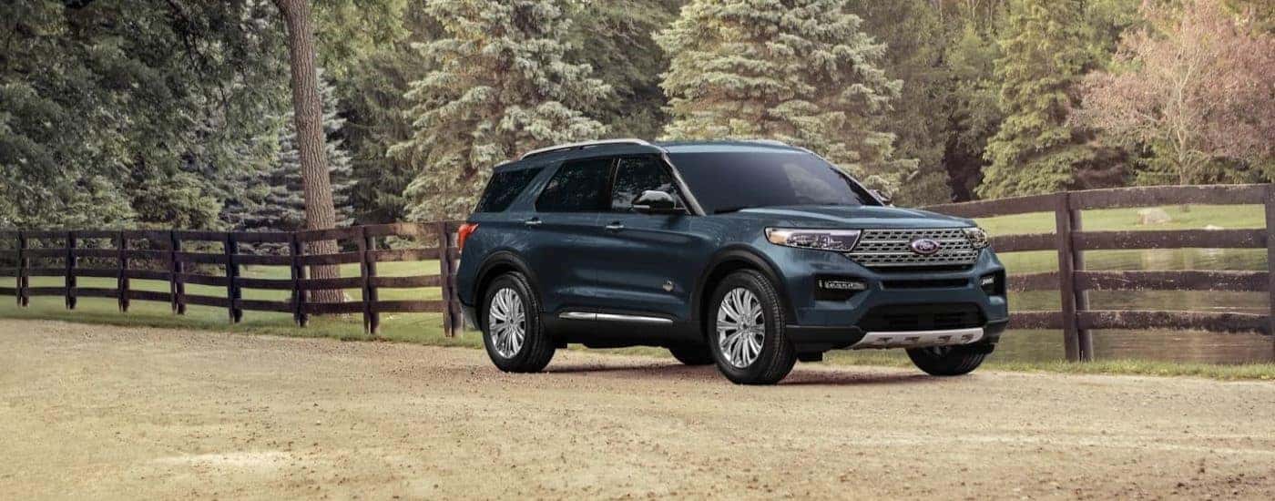 A blue 2024 Ford Explorer King Ranch is shown parked on a dirt road.