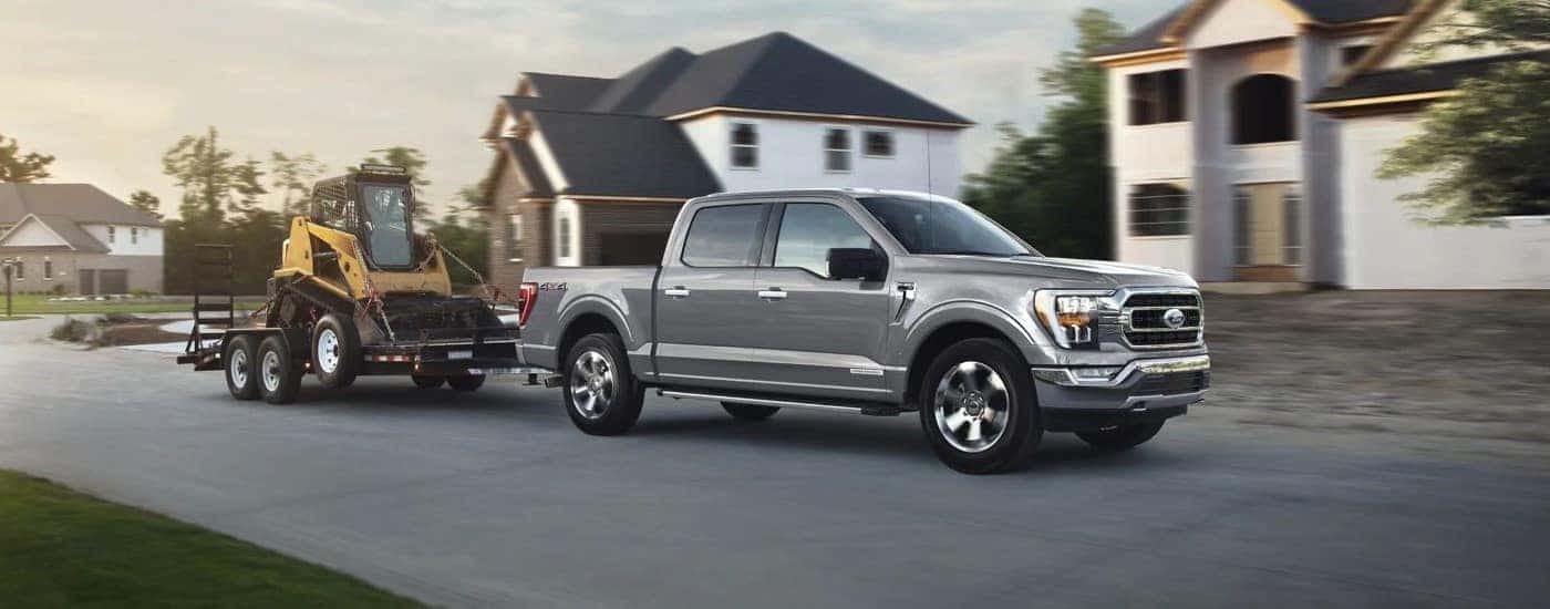 A silver Ford F-150 towing a tractor.