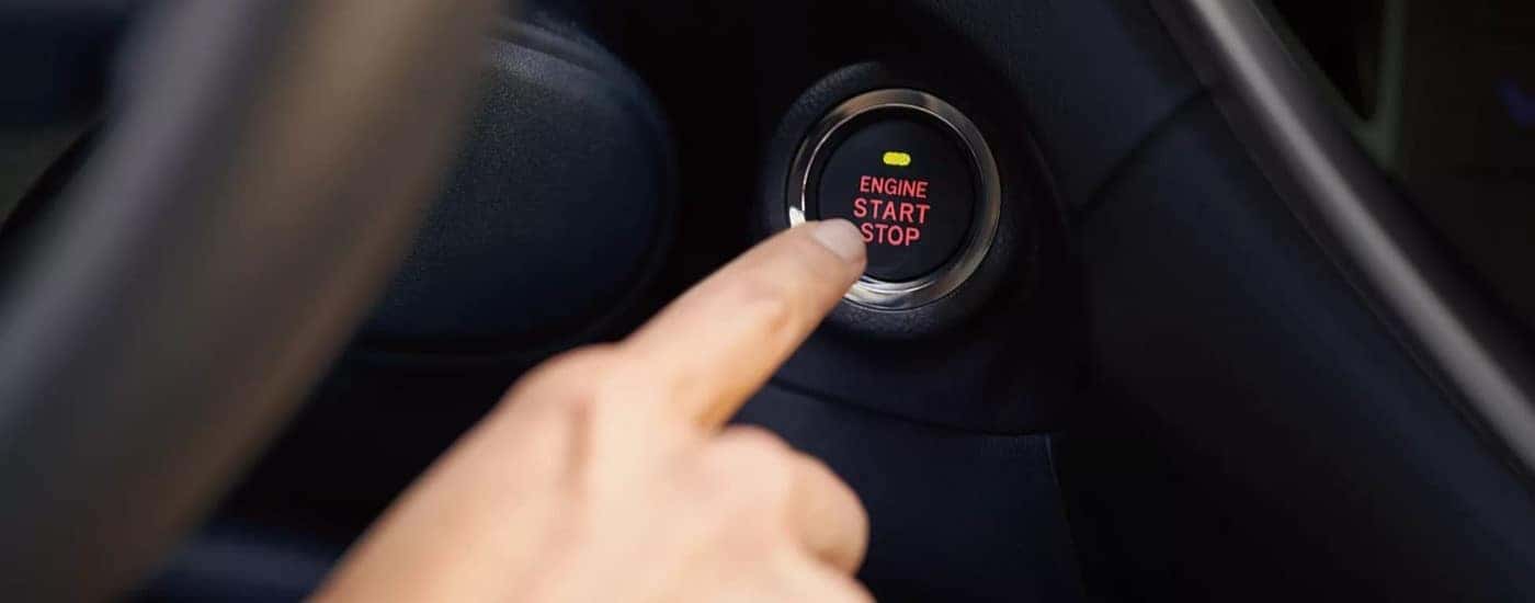 A person pressing a push-start button.