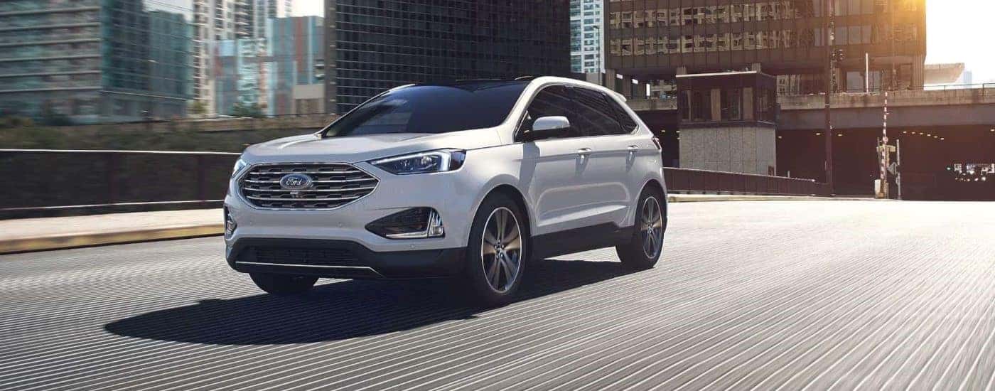 A white 2024 Ford Edge shown driving down the street.