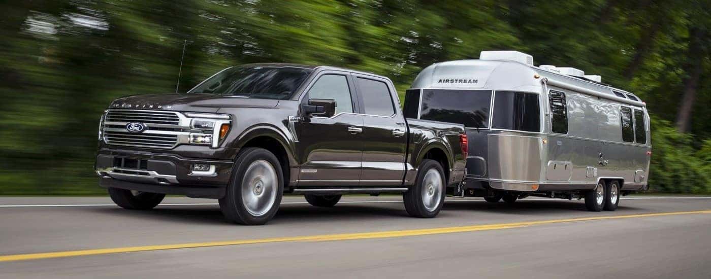 A black 2024 Ford F-150 is shown towing an Airstream trailer.