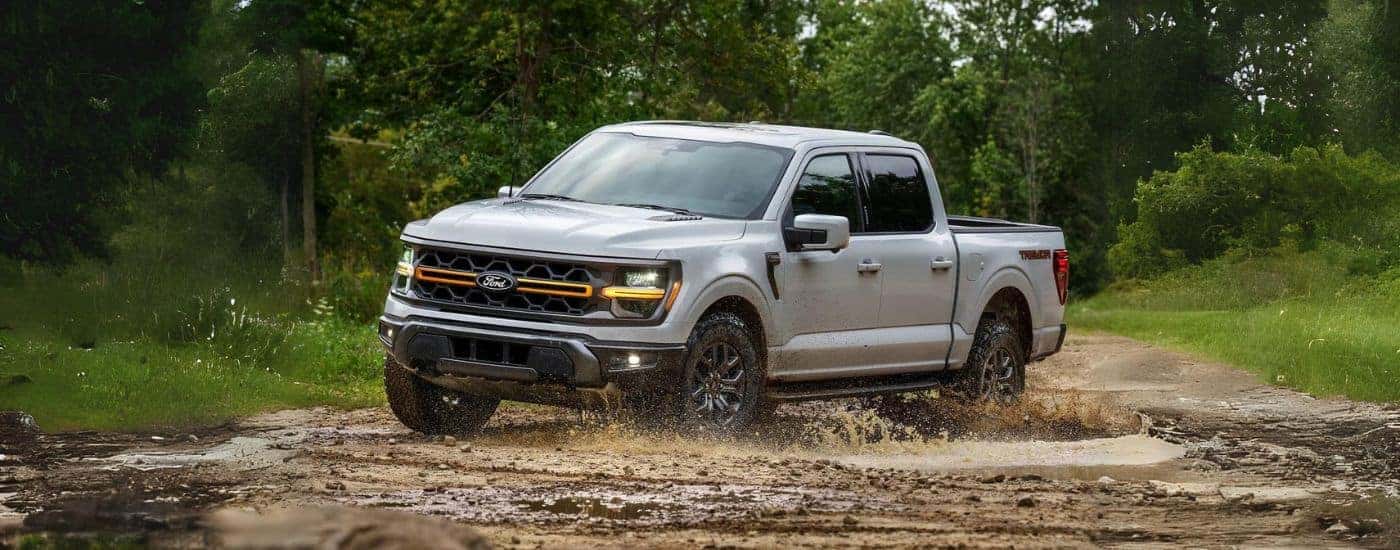 A grey 2025 Ford F-150 Tremor off-roading in mud.