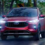 Red 2026 Ford Escape driving on a rainy road.