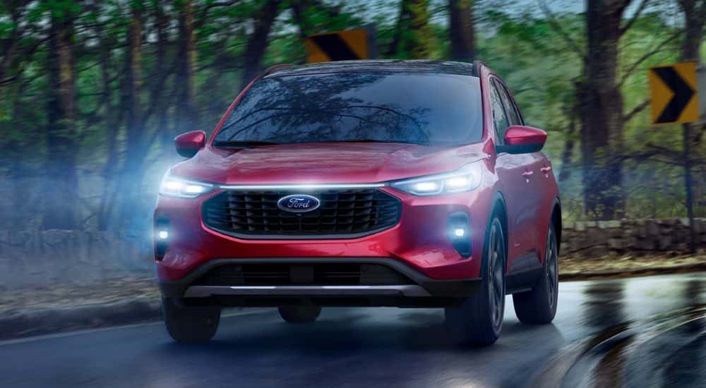 Red 2026 Ford Escape driving on a rainy road.