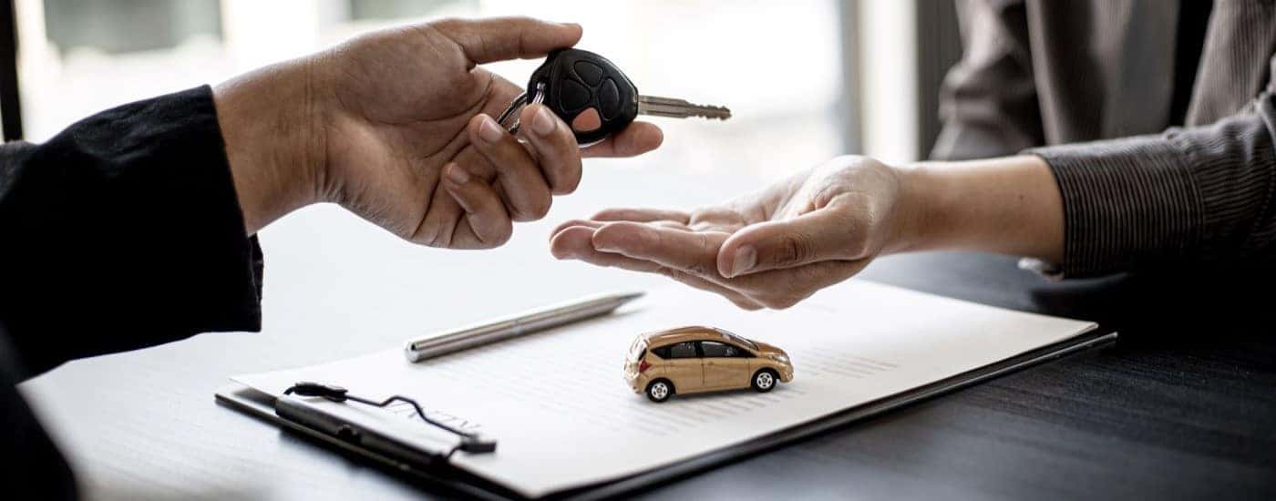 A person handing a car key to another person.