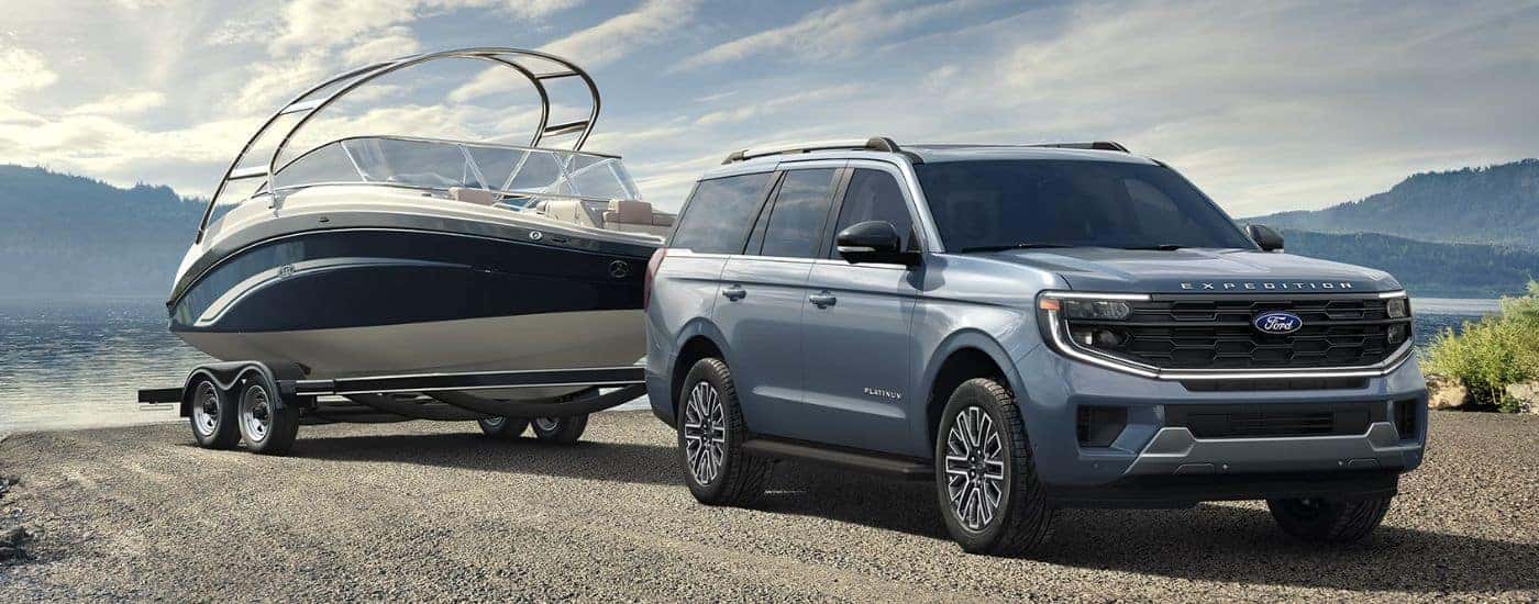Blue 2026 Ford Expedition Platinum towing a boat near a lake