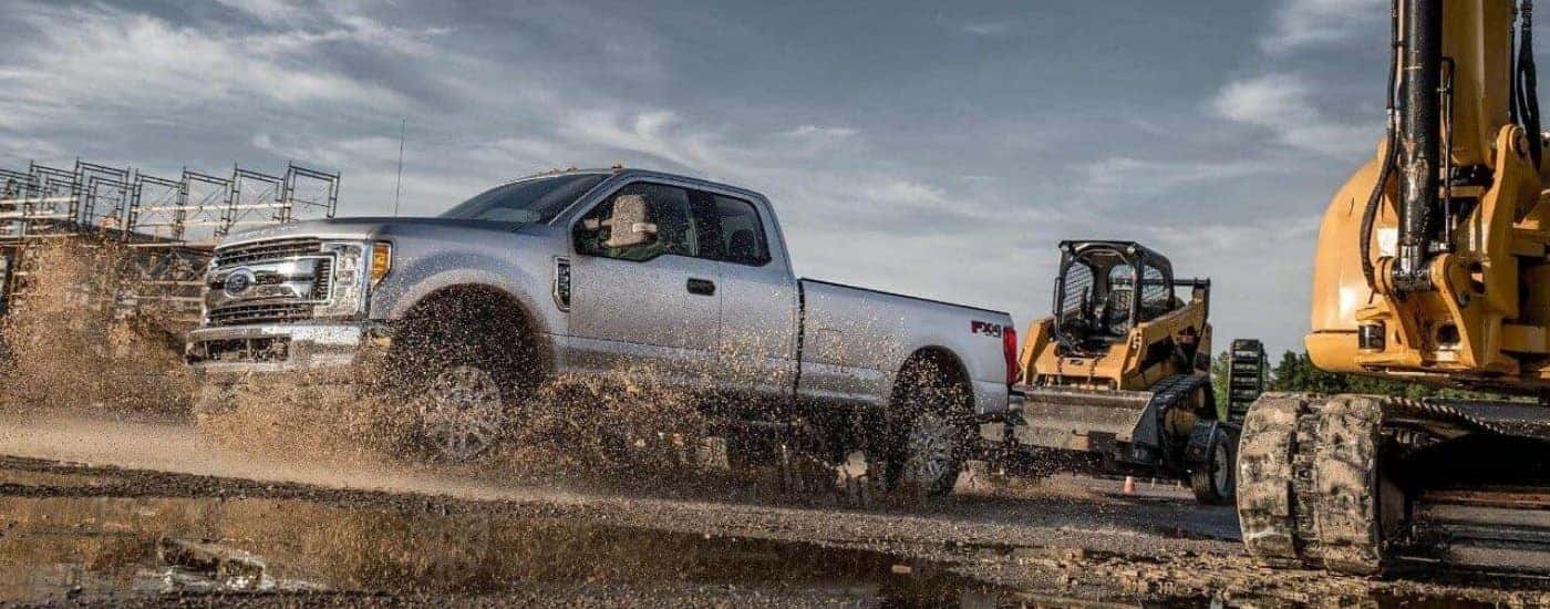 Silver 2018 Ford F-350 FX4 driving through a puddle on a construction site.