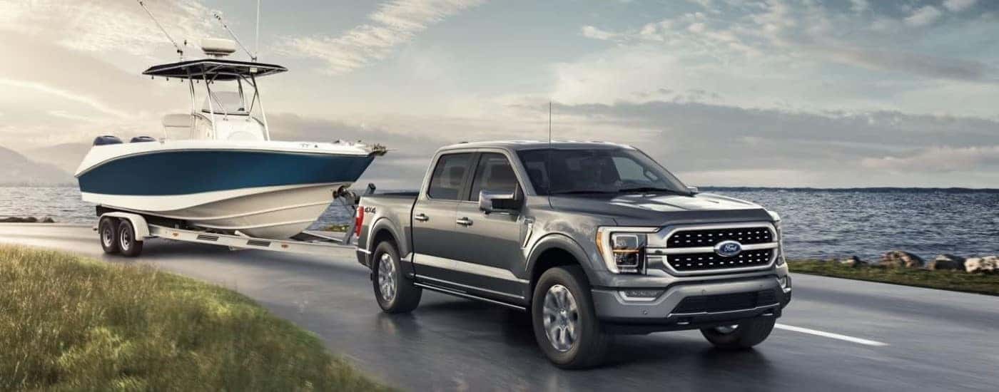 Grey 2022 Ford F-150 Limited towing a boat near a body of water.