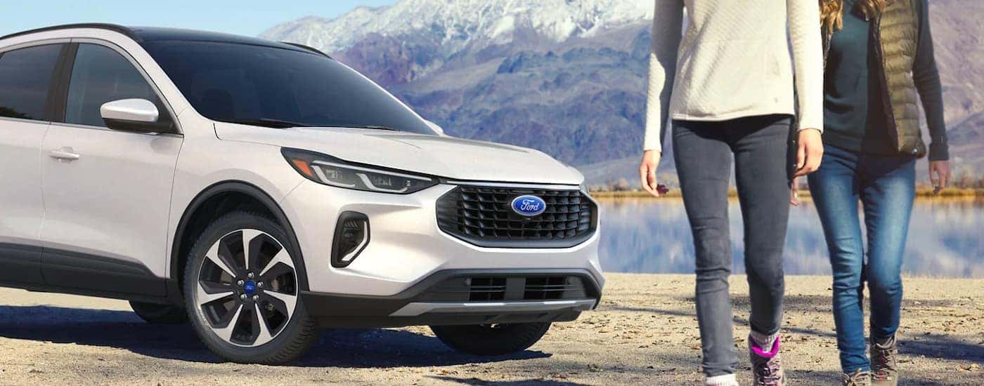 Two people walking away from a white 2023 Ford Escape