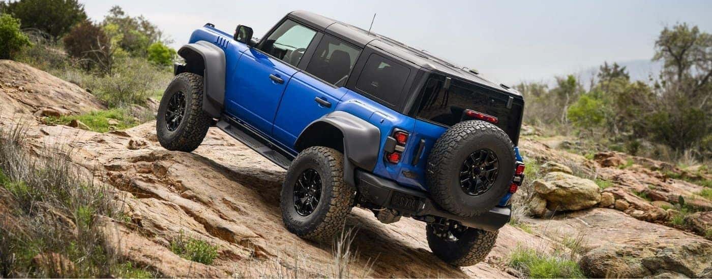 Blue 2026 Ford Bronco Raptor driving up rocks