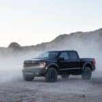 A black 2021 Ford F-150 Raptor is shown with dust settling after leaving a Ford dealer near you.