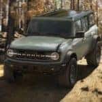 A green 2021 Ford Bronco Wildtrack 4 door is off-roading in the woods.