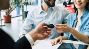 A couple is being handed keys after filling out paperwork at a Shelbyville used Ford dealership.