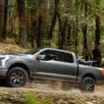 A grey 2022 Ford F-150 Lighting is shown driving through the woods after leaving a Tennessee Ford truck dealer.