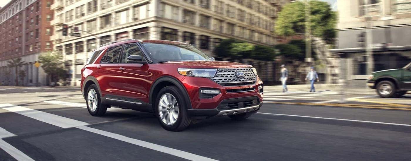 A red 2022 Ford Explorer is shown driving on a city street.