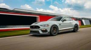 A pale blue 2021 Ford Mustang Mach 1 is shown driving on a race track.