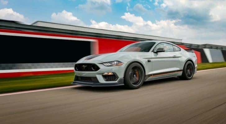 A pale blue 2021 Ford Mustang Mach 1 is shown driving on a race track.