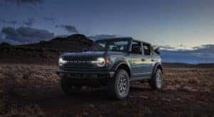 A blue 2021 Ford Bronco is shown from the side parked in a desert.