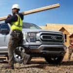 A construction worker is shown walking in front of a silver 2021 Ford F-150 XLT.