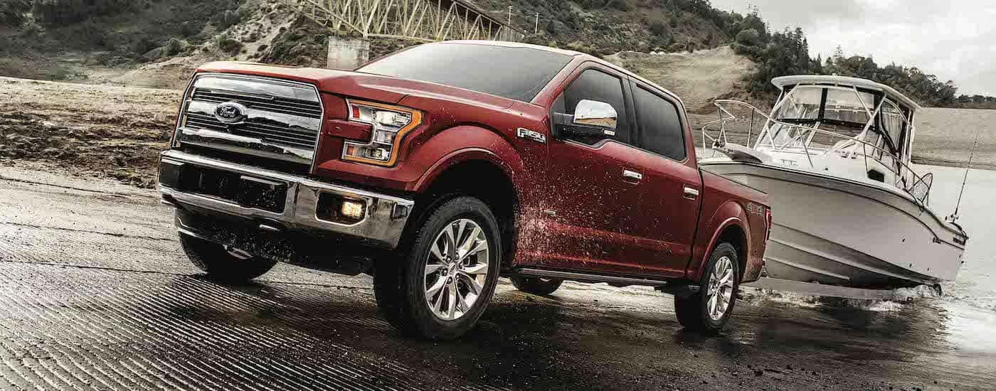 A red 2017 Ford F-150 is shown towing a boat out of a body of water.