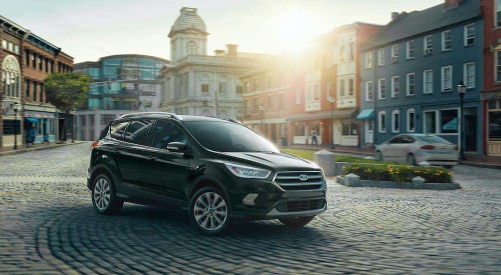 A black 2018 Ford Escape is shown in a city on a paver pathway.