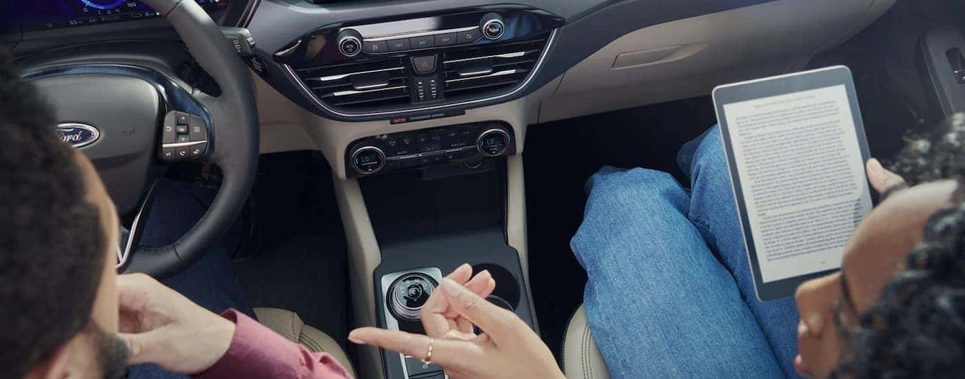 Two people are shown sitting in the front seats of a 2021 Ford Escape.