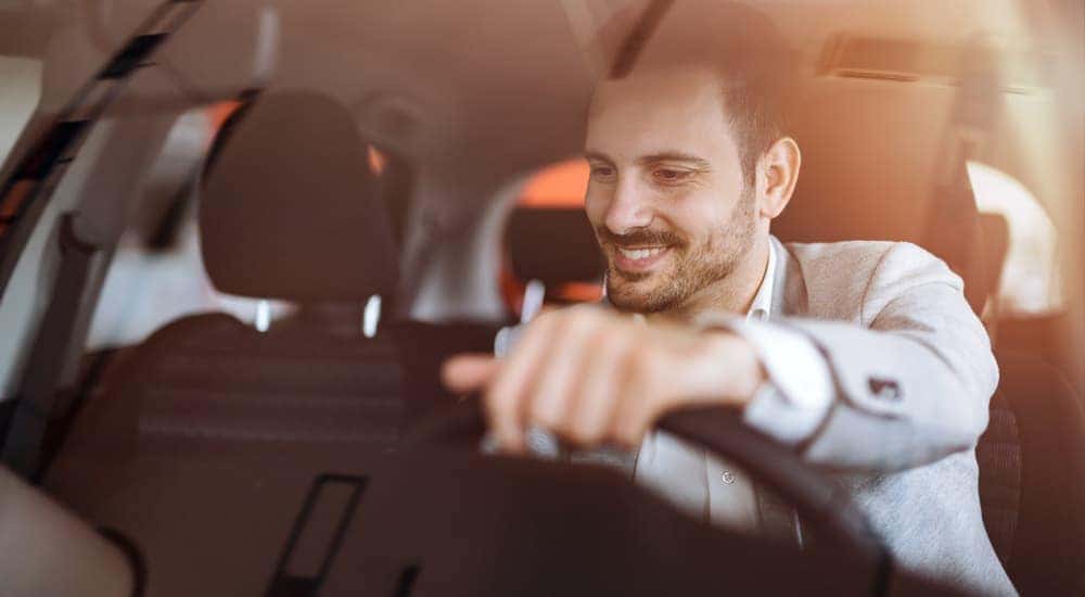 A man is shown sitting in the front seat of a vehicle.