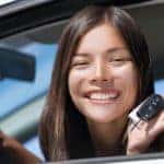 A teen is shown holding a car key at a used car lot near you.