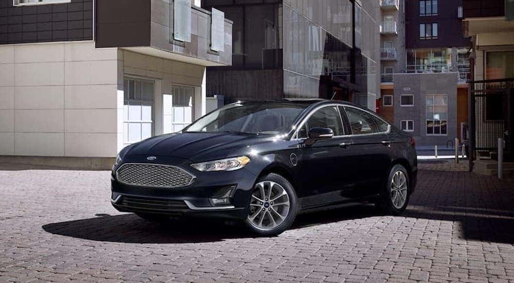 A black 2020 Ford Fusion parked on a modern industrial city street