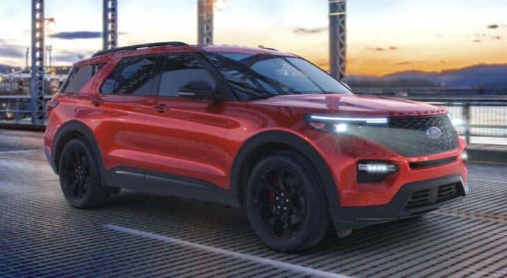 A red 2023 Ford Explorer is shown driving over a bridge.