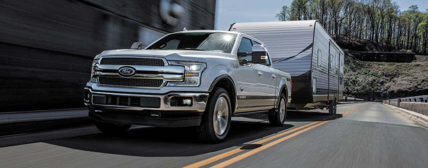 One of the most popular certified Fords for sale, a white 2018 Ford F-150, is shown towing a trailer.