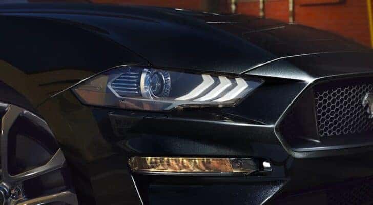 A close up shows the passenger side headlight on a black 2021 Ford Mustang.