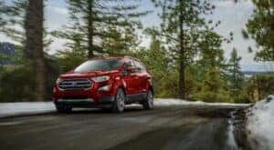 A red 2022 Ford EcoSport is shown driving on a forest road.