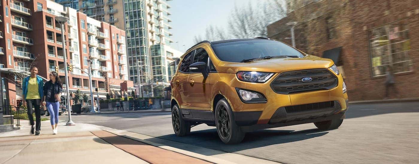 A gold 2022 Ford EcoSport is shown driving on a city street.