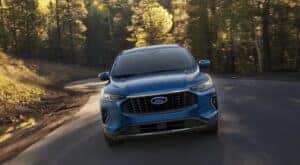 A blue 2023 Ford Escape is shown from the front driving on an open road.
