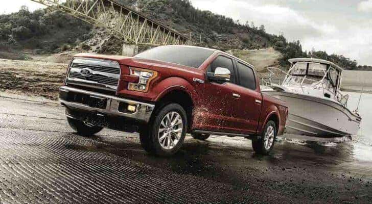 A red 2017 Ford F-150 is shown from the front at an angle while towing a boat.