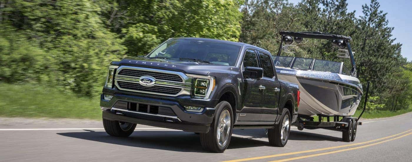 A grey 2022 Ford F-150 is shown from the front while towing a boat after leaving a dealer that had a Ford F-150 for sale.