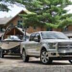 A white 2016 Ford F-150 Limited is shown towing a boat.