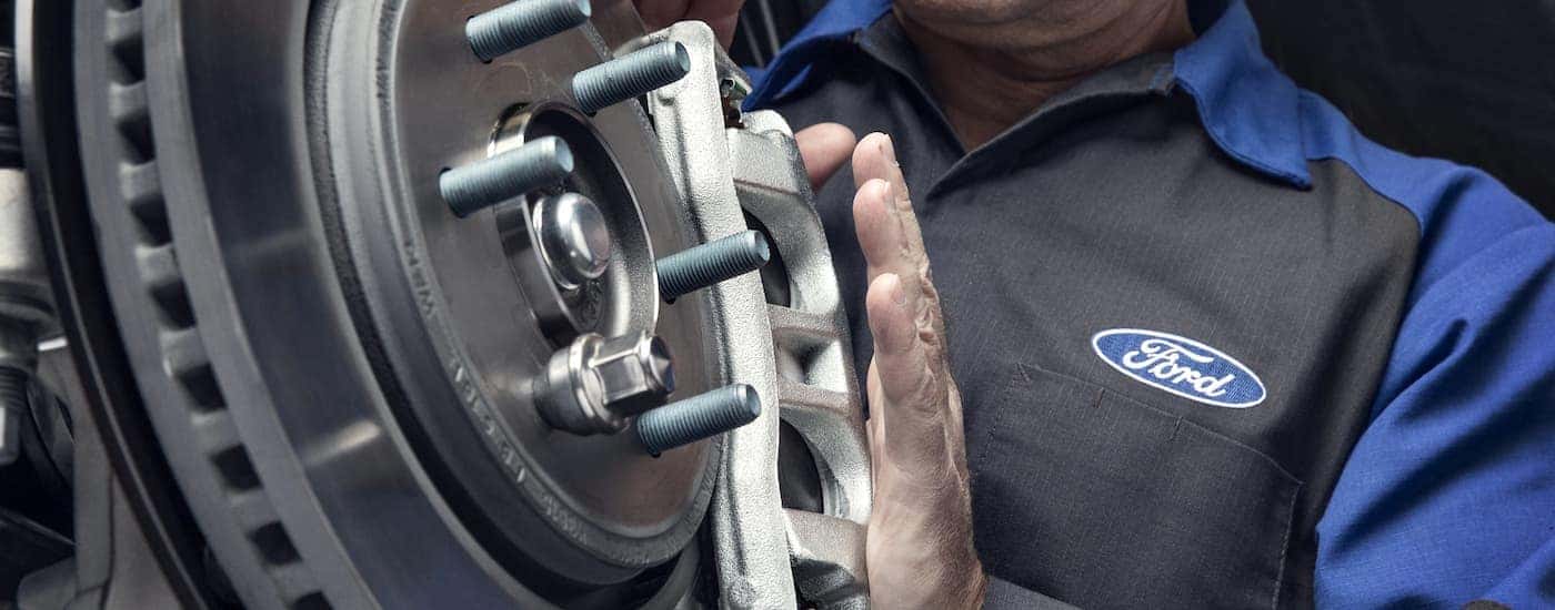 A close up of a Ford mechanic is shown inspecting the brakes at a certified ford truck dealer.