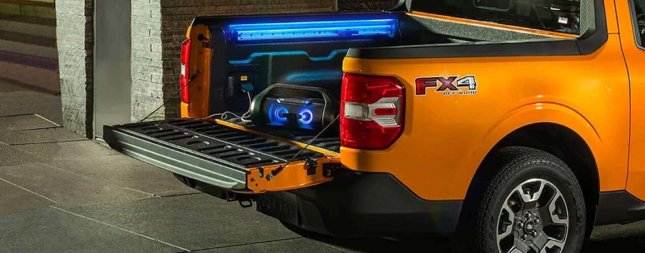 A yellow 2023 Ford Maverick FX4 is shown with a boombox in the bed.