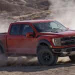 A red 2023 Ford F-150 Raptor is shown from the side while off-road.