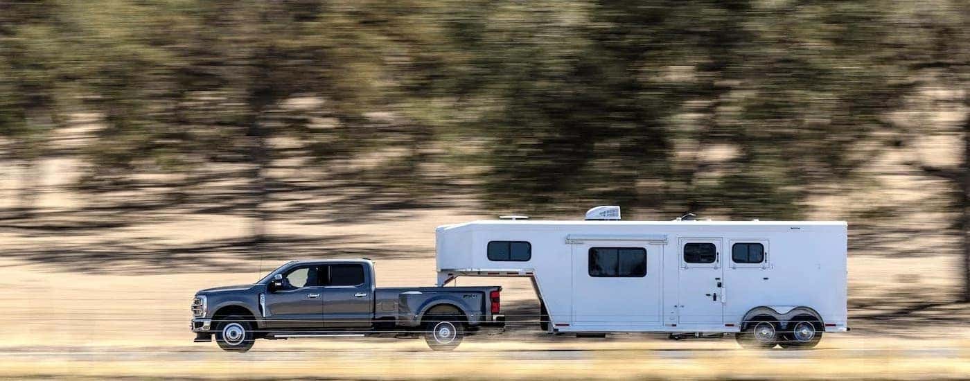 A grey 2023 Ford F-350 is shown from the side while towing a trailer after leaving a dealer that has Super Duty trucks for sale near Murfreesboro.
