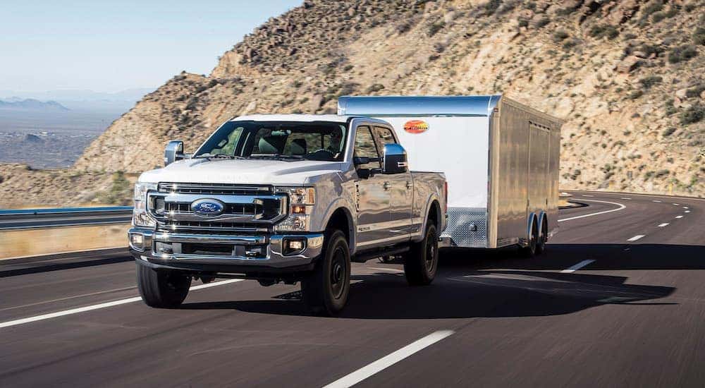 A white 2020 Ford F-350 is shown towing a trailer on a highway.