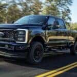 A black 2023 Ford F-250 XL STX is shown driving on a highway after viewing super duty trucks for sale near Murfreesboro.