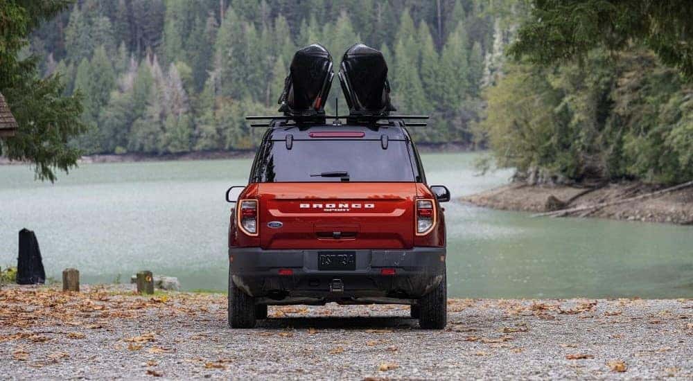 An orange/red 2023 Ford Bronco Sport is shown from the rear parked at a lake.