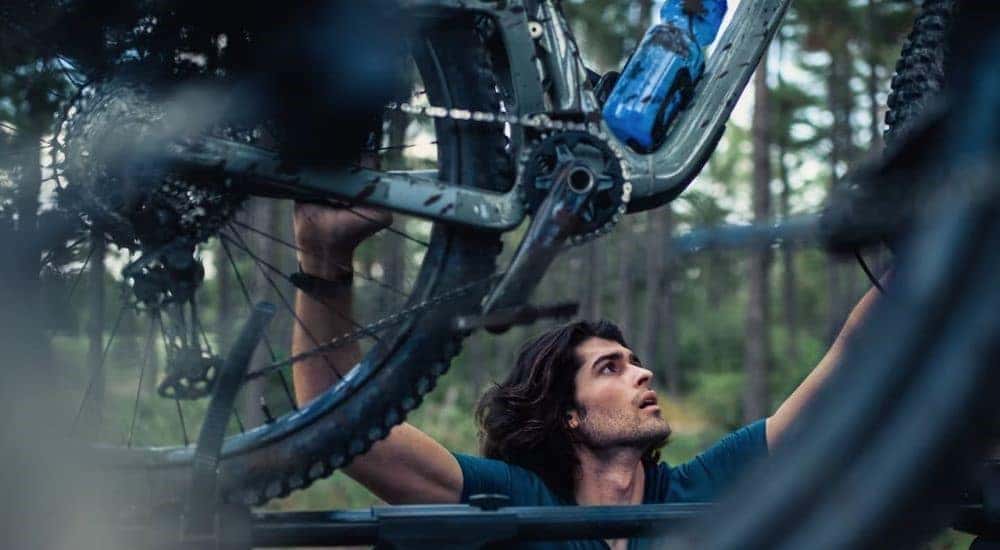A person is shown securing bikes on the roof 2023 Ford Bronco Sport for sale.