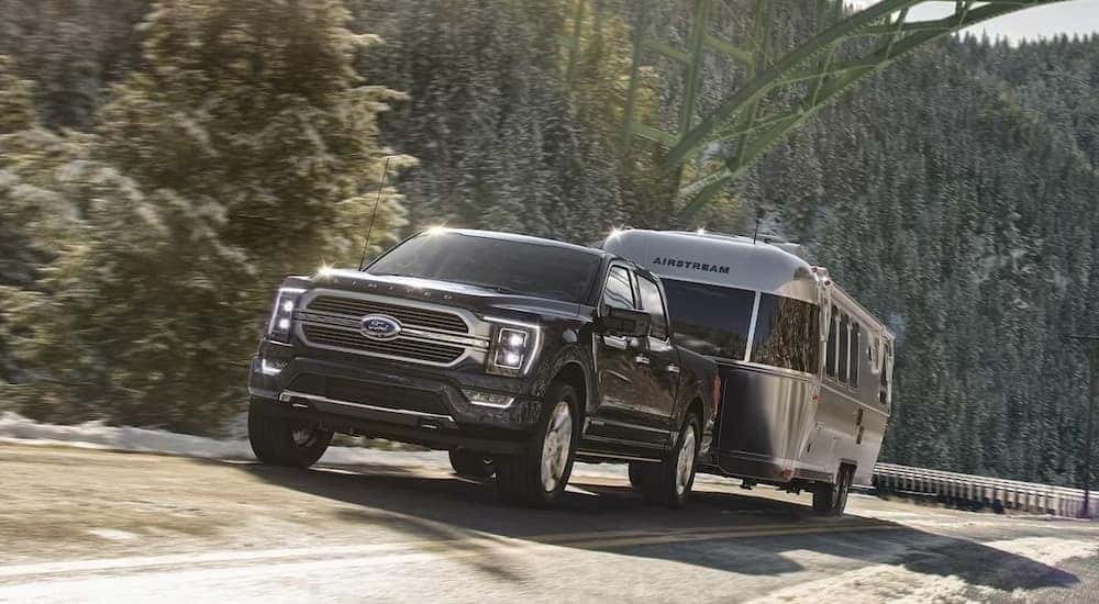 A black 2023 Ford F-50 Limited is shown towing a trailer.