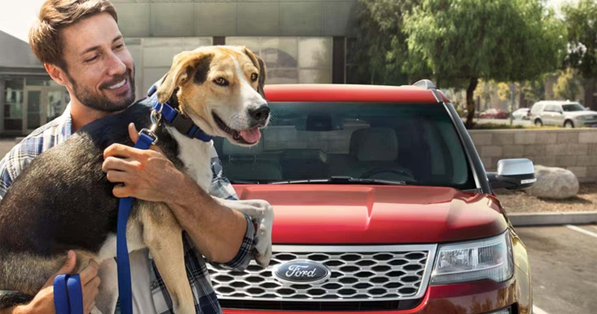 Person and a dog standing in front of a certified pre-owned ford