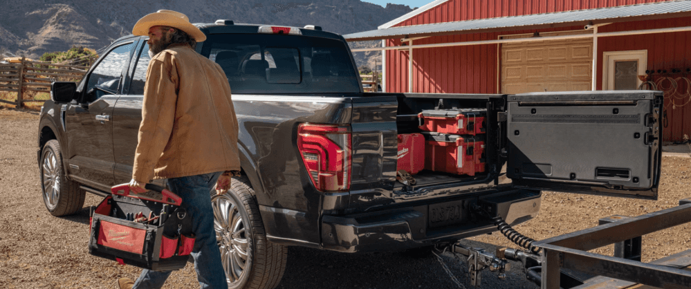 A rancher walking past a grey Ford F-150 with the truck bed open.