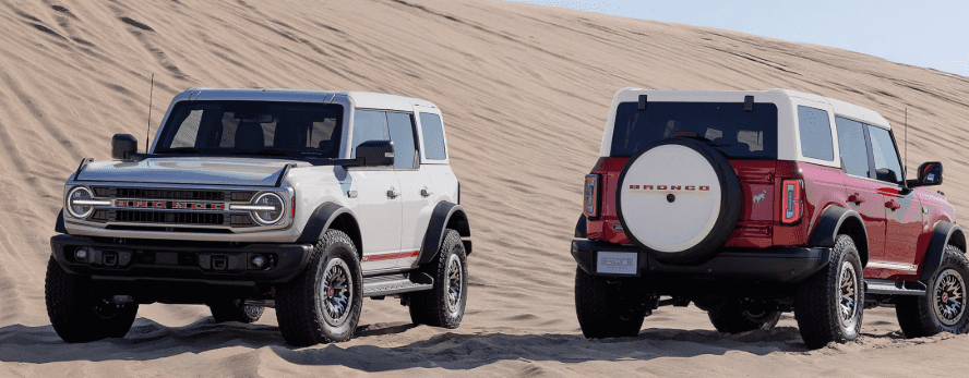 A white and red Ford Bronco in a desert facing in opposite directions